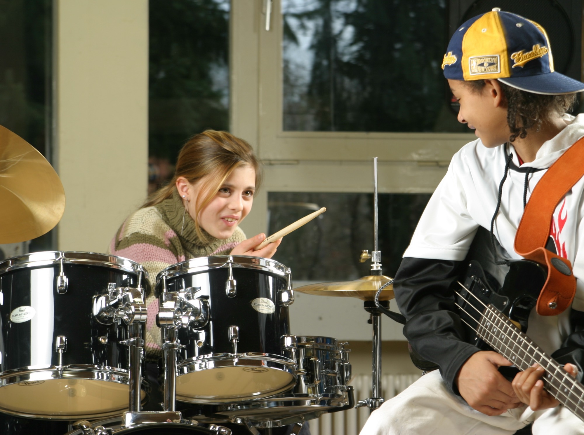 Eine Schülerin am Schlagzeug lacht einem Bassisten zu